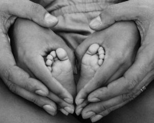 grayscale photo of person holding feet and hands