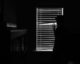 Silhouette of a person looking through window blinds in a dark room. Mystery and introspection.