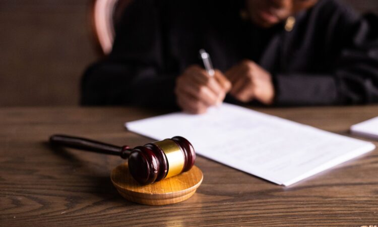 Judge signing documents at desk with focus on gavel, representing law and justice.
