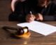 Judge signing documents at desk with focus on gavel, representing law and justice.