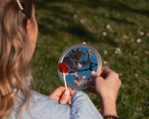 woman reflecting cherry blossoms in handheld mirror